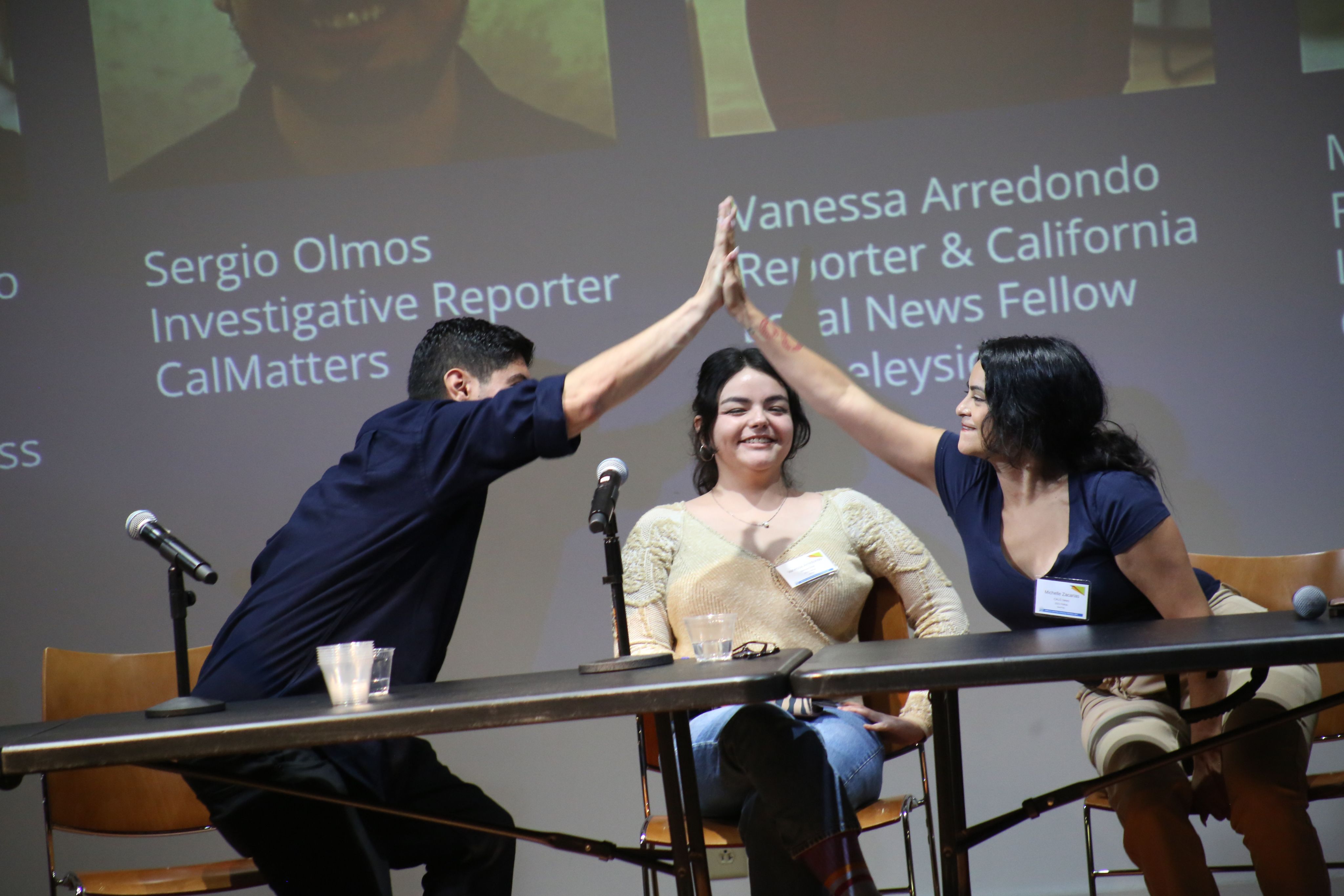 two people high five with third person in center of it