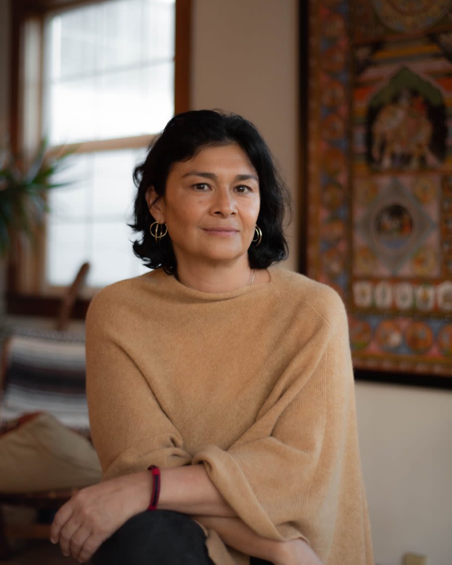 woman in brown sweater looking directly at the camera