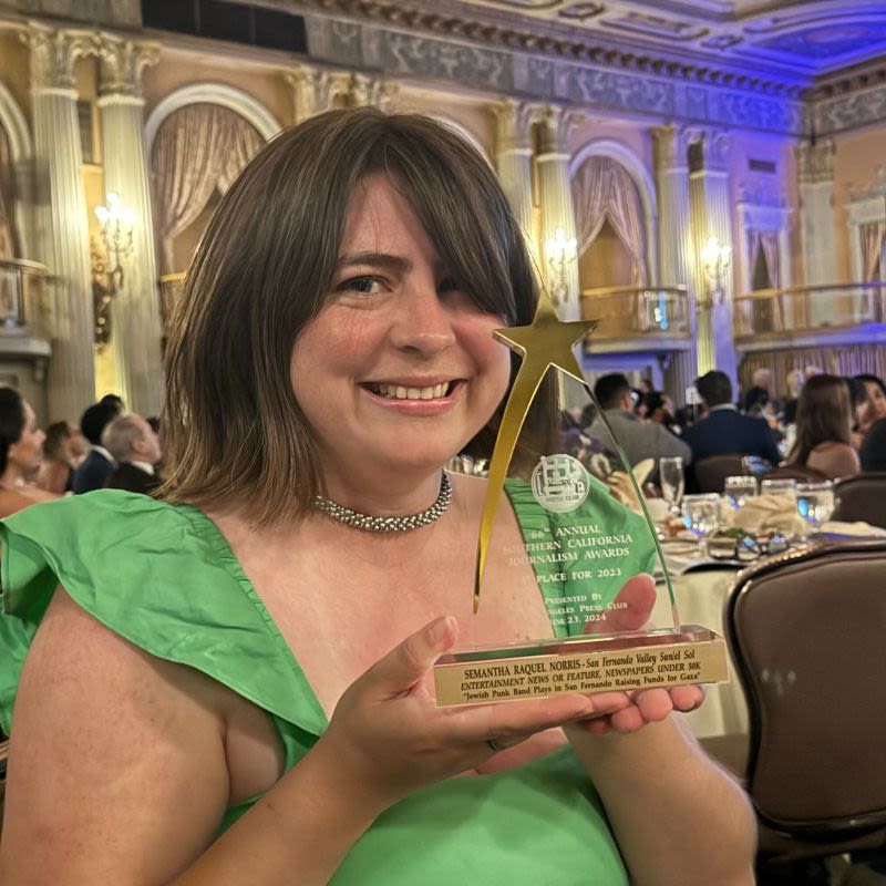 The face of a woman smiling and holding an award. 