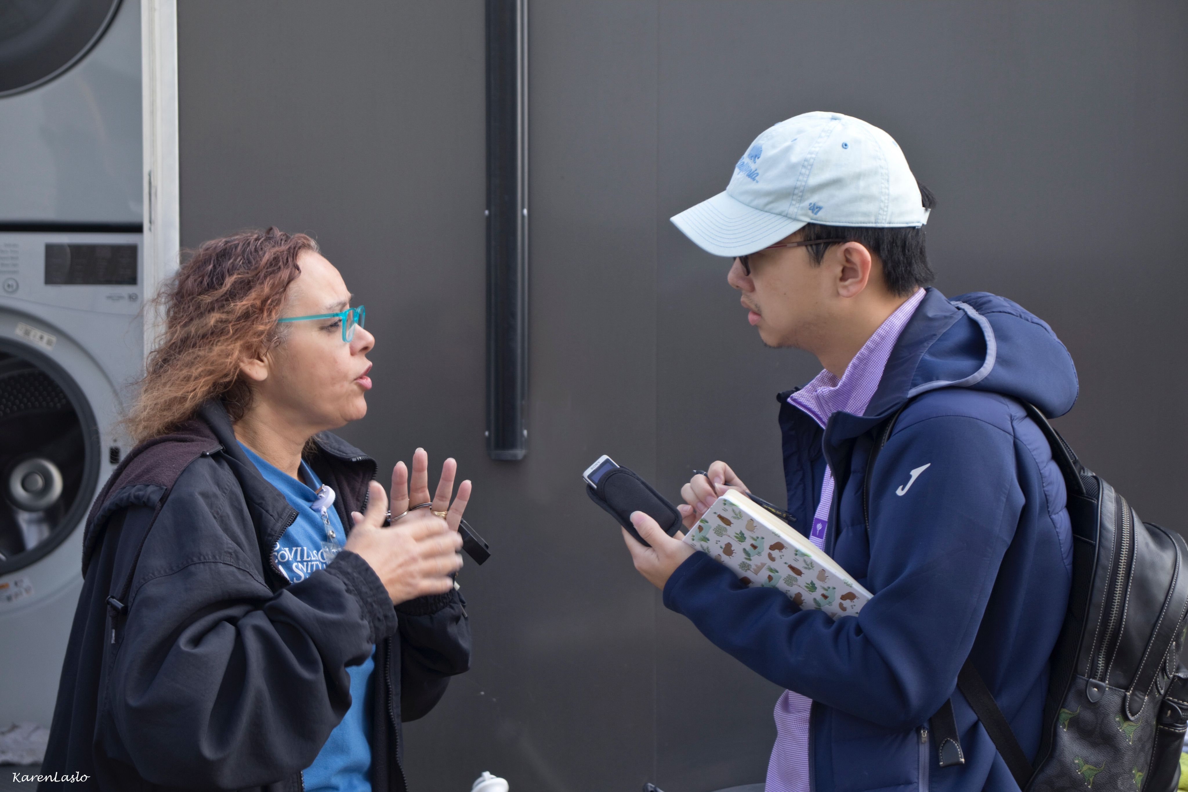 A  woman talks in an animated way to a man with a tape recorder. 