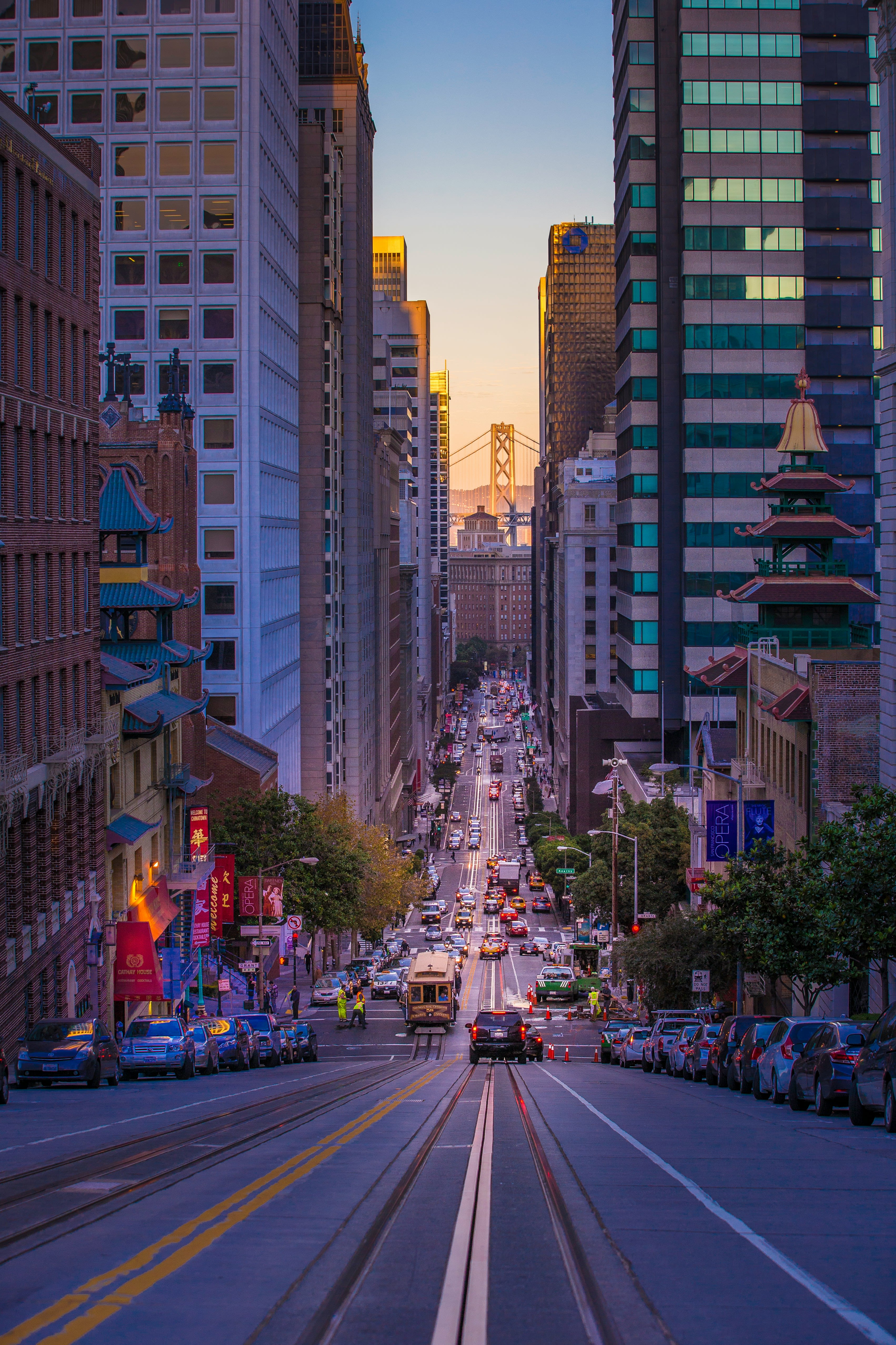Street scene in San Francisco, with Golden Gate Bridge peaking through city buildings. 