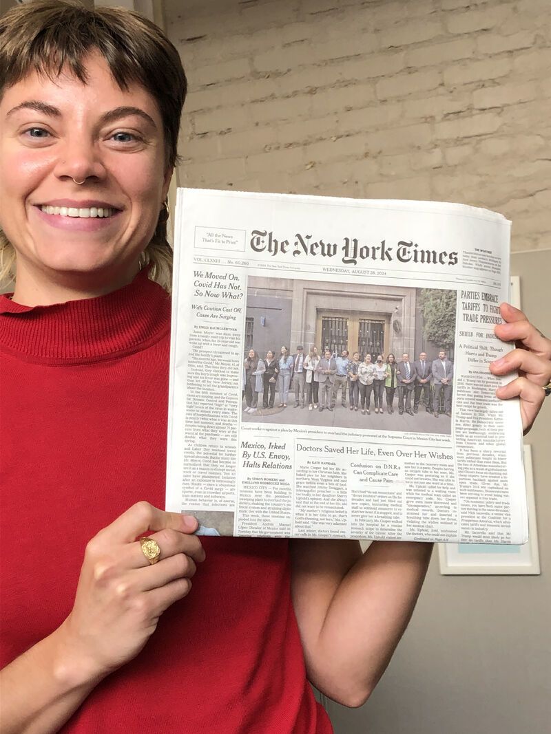 Photo of Kate Raphael holding a copy of the NY Times where her investigative piece was published