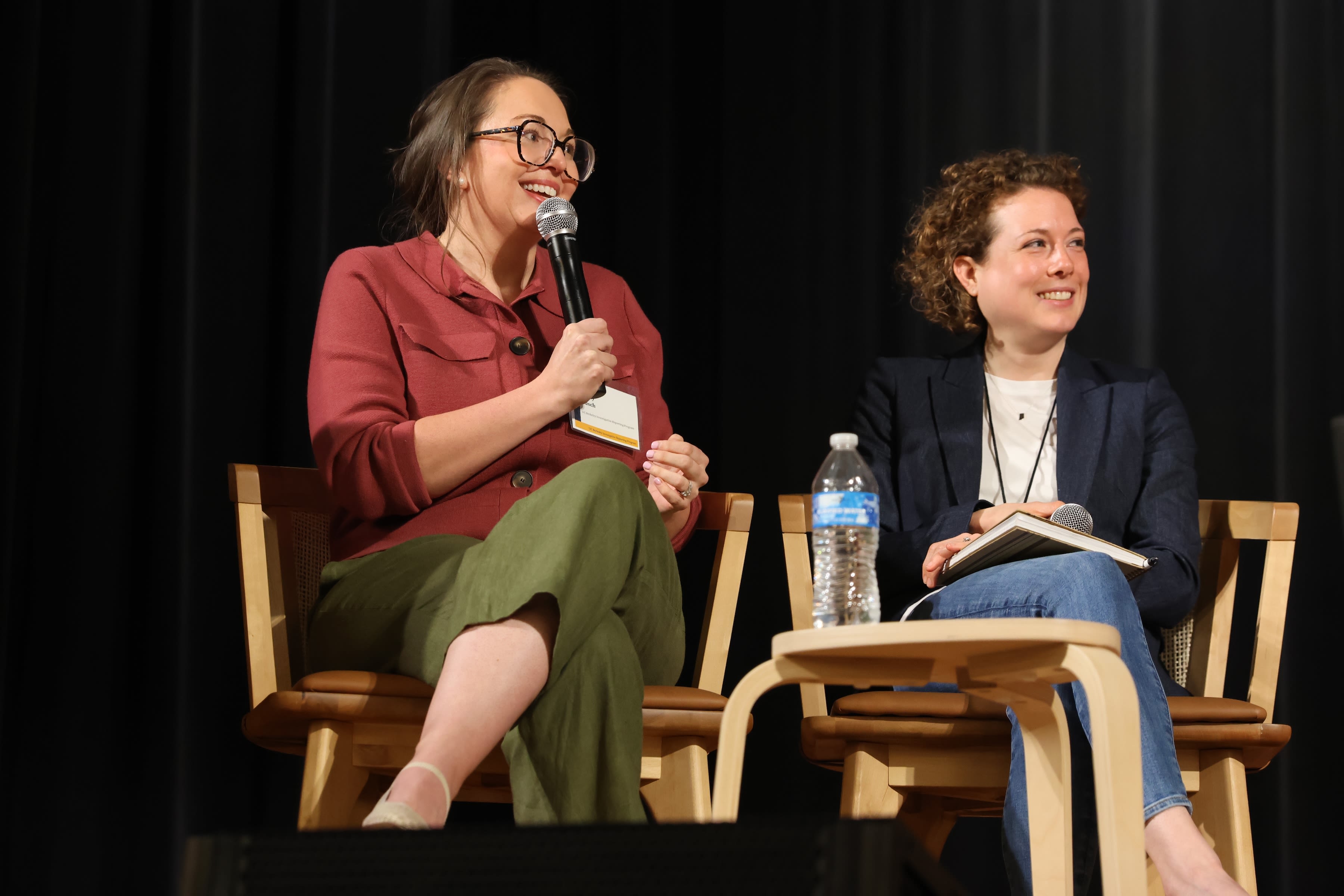 Two people on stage looking to the left of the camera off stage. 
