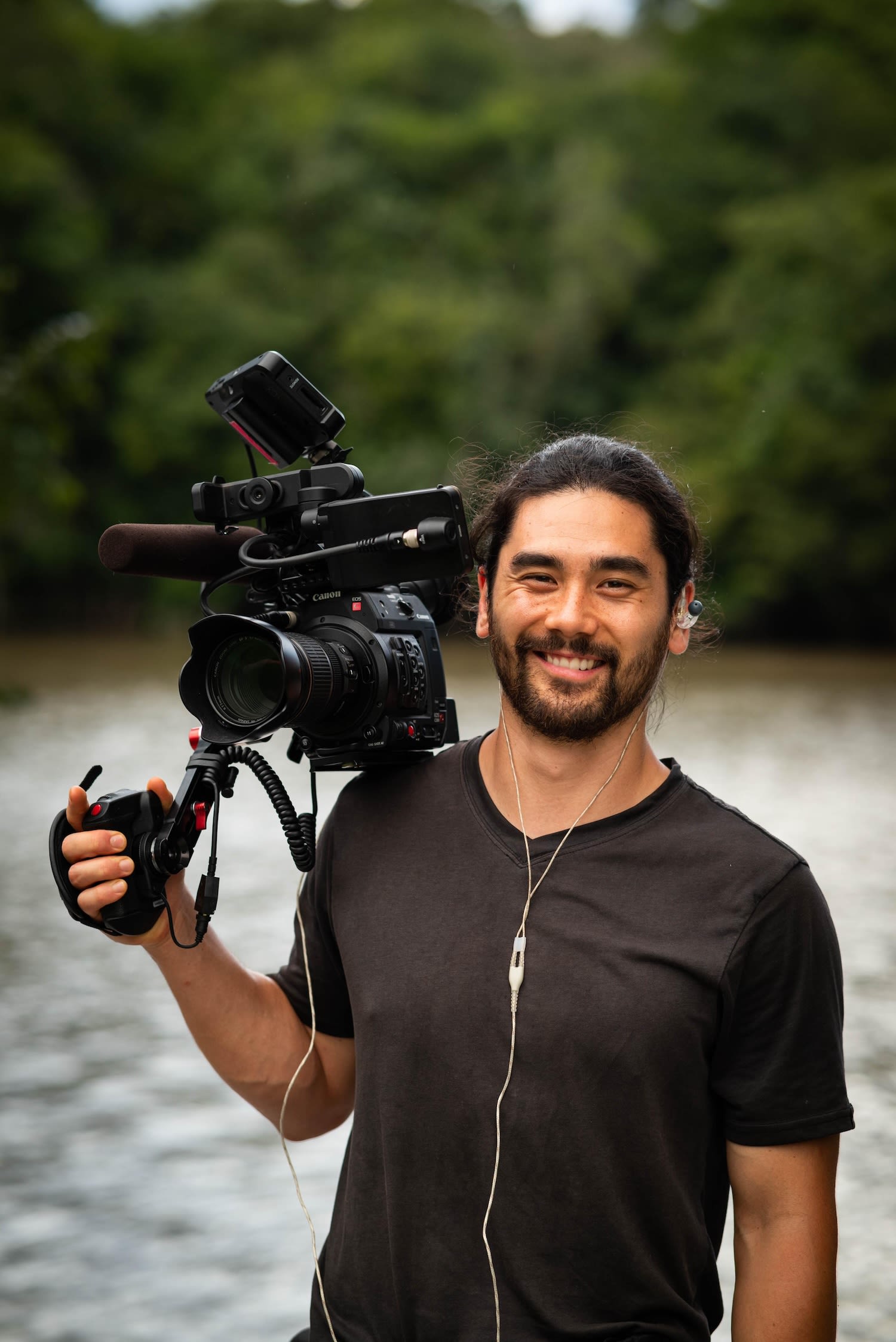 Sasha Schell, then an IRP student, holds a camera while on a shoot in Brazil. He's wearing a black t-shirt and smiling at the camera.