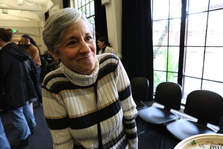 A woman in a turtle neck striped sweater makes a closed mouth smile. She is Christine Schiavo.
