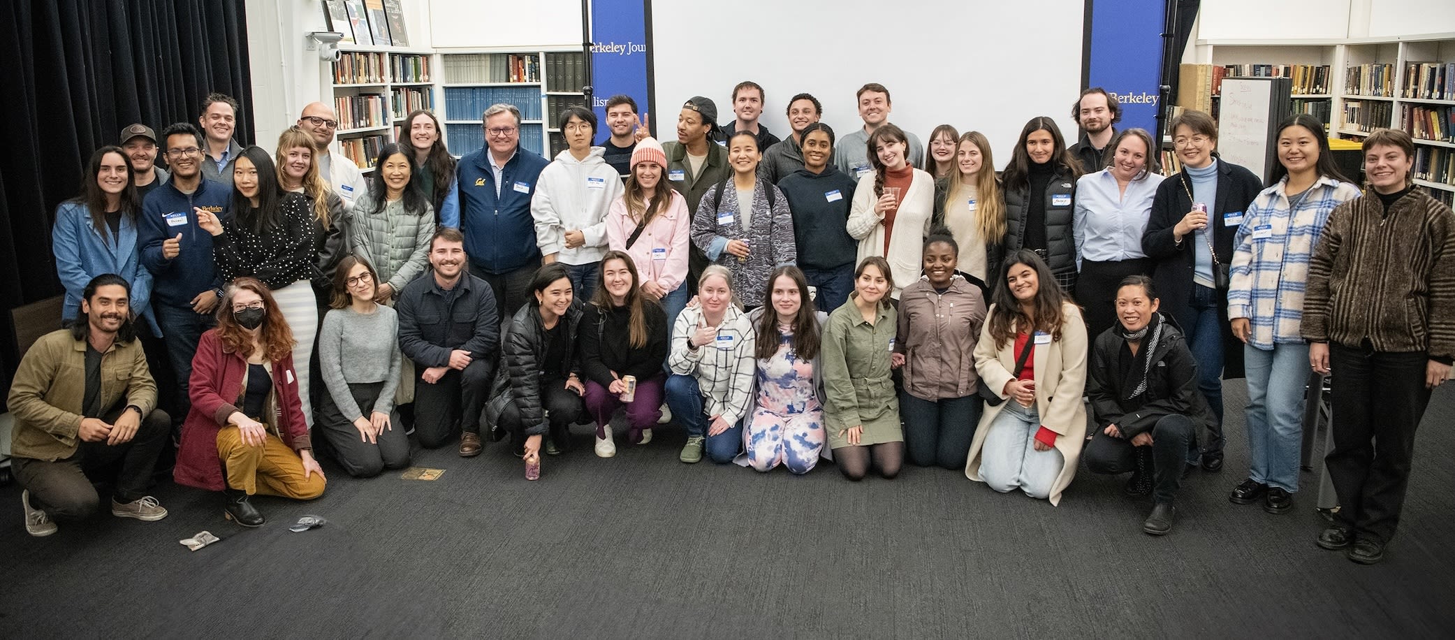 A large group of diverse people pose for a group photo in UC Berkeley Journalism's LMC. 