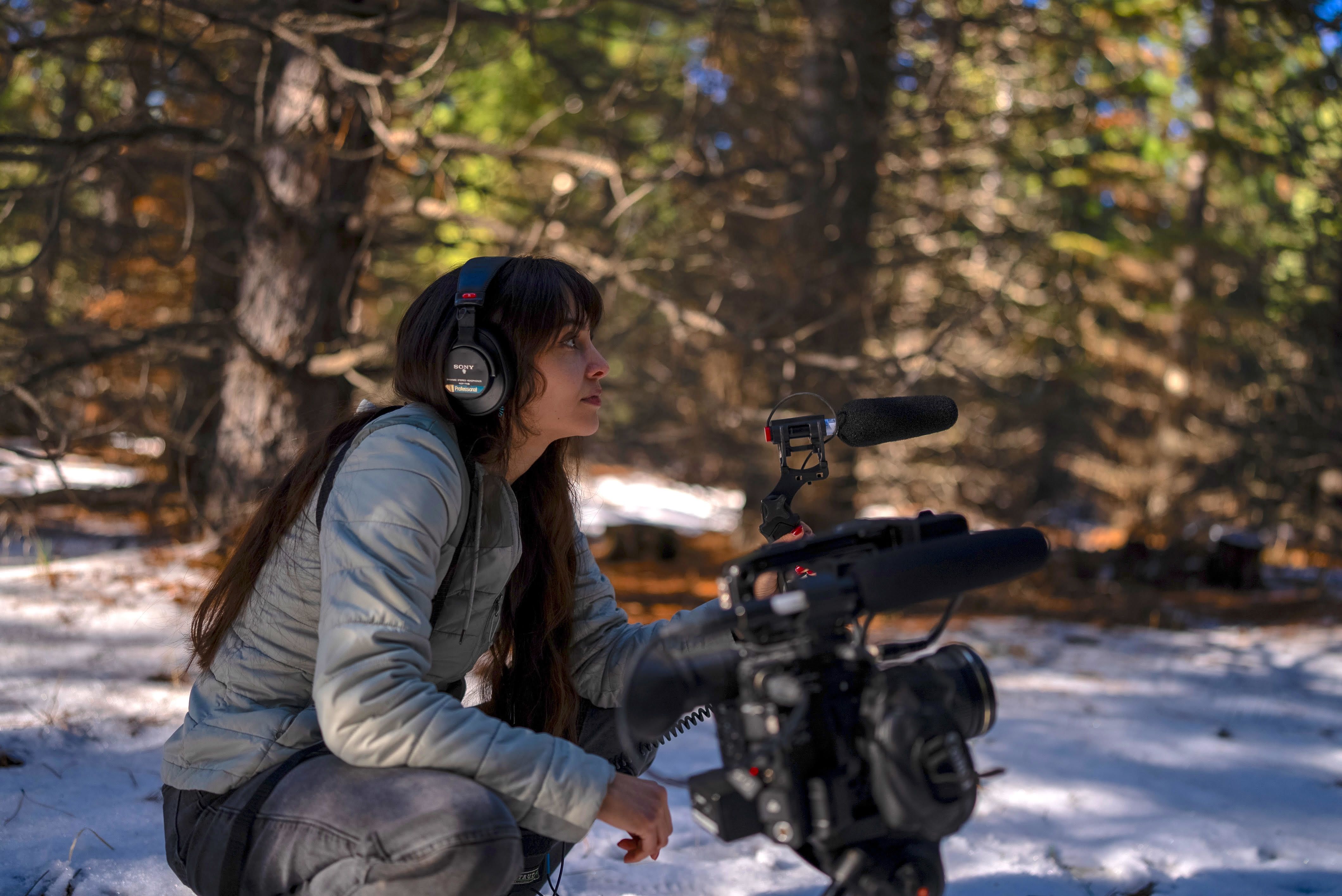 Cover image of a documentary student filming in the woods. 