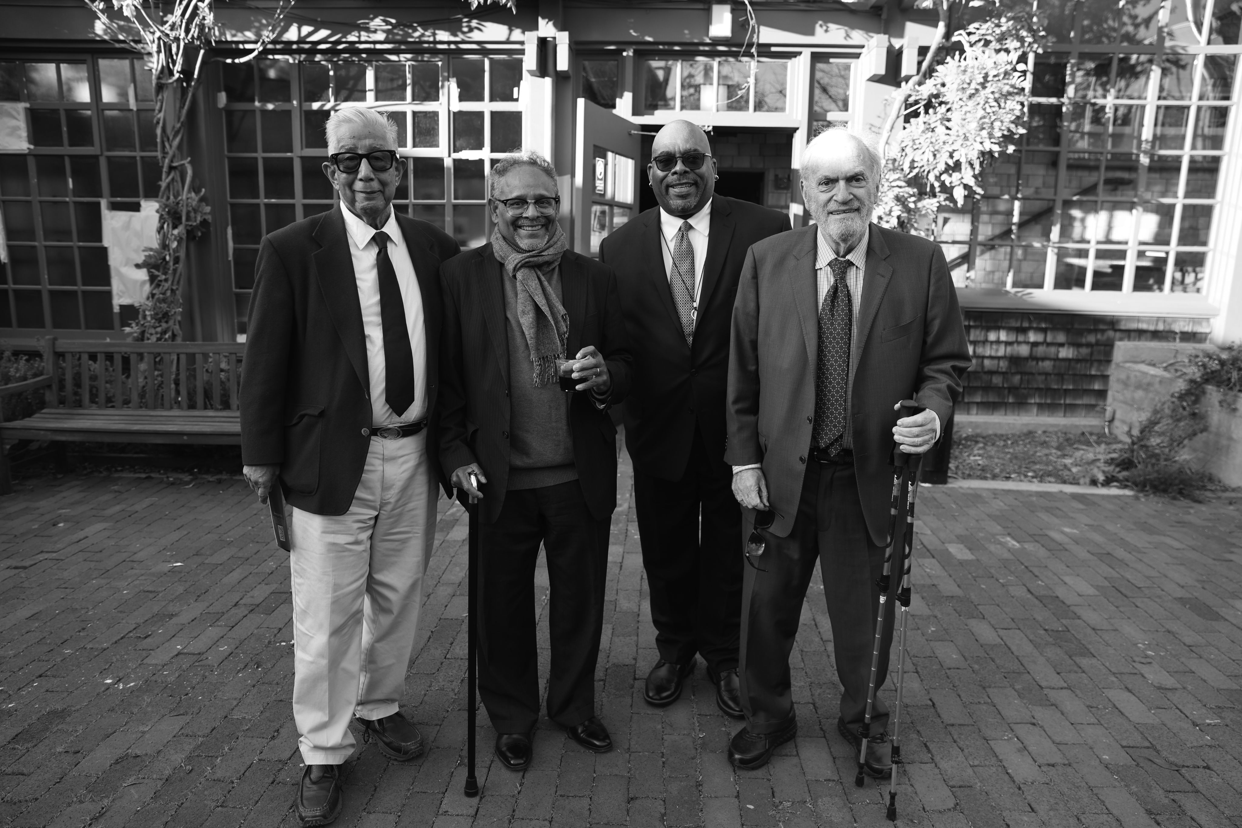 Four men in the Journalism School's courtyard. The photo is in black and white. 